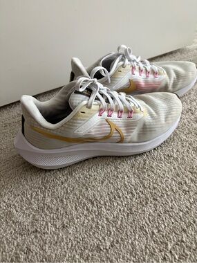 Nike Women’s Running Shoes in White with Gold Swoosh and Pink Accents